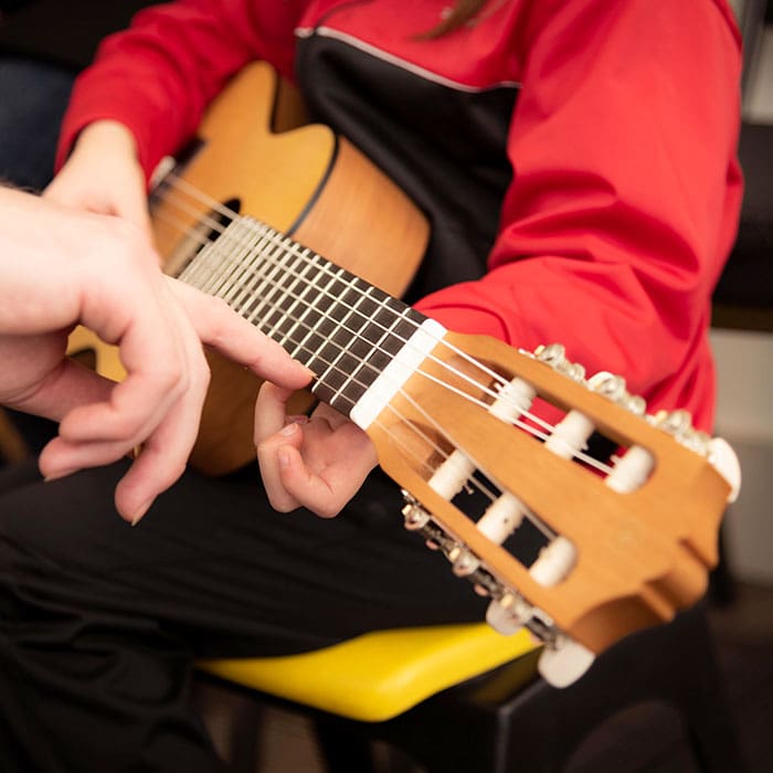 Kind beim Gitarre spielen mit einem Lehrer